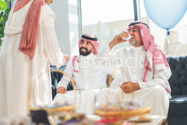 مرأه عربية سعودية تقوم بتقديم القهوه العربية على العائلة ، مشاركة لأجواء رائعة لعائلة سعودية داخل المنزل تحتفل بعيد الفطر السعيد ، عيد فطر مبارك ،  الزيارات العائلية وتجمعات الأسر
