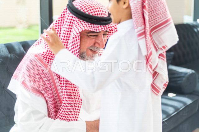 طفل سعودي خليجي سعيد ، يرتدي لباس العيد الانيق ، يقبل جده و يهنئه بقدوم العيد  ، الاحتفال بعيد الفطر السعيد ، عيد الفطر المبارك 