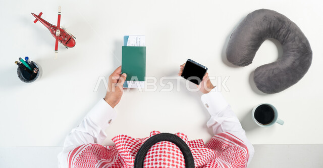 Buying airline tickets online, using websites to search for flights, a close-up portrait of a Saudi Gulf Arab man using a mobile phone with a ticket and passport in his hand, a cup of coffee next to him and miniature models of airplanes, showing a blank black screen, white background