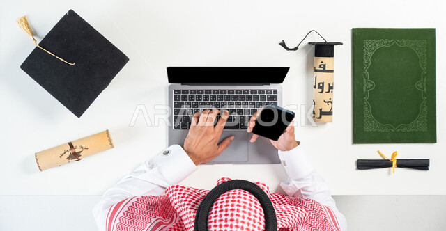 استخدام تطبيقات التسوق عن بعد، بورتريه ليدي رجل عربي خليجي سعودي يقوم باستخدام الحاسوب المحمول والجوال، الاستفادة من التكنولوجيا الحديثة لطلب مستلزمات التخرج أونلاين، البيع والشراء عبر الانترنت، عرض شاشة سوداء فارغة، خلفية بيضاء