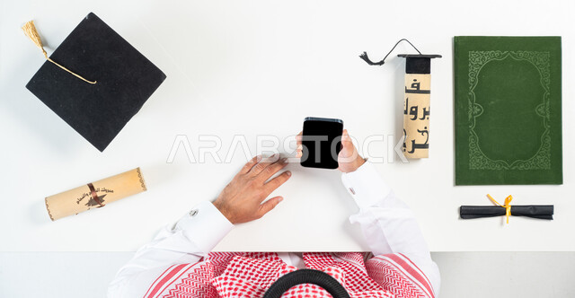 استخدام تطبيقات التسوق عن بعد، الاستفادة من التكنولوجيا الحديثة لطلب مستلزمات التخرج عن طريق الأونلاين، البيع والشراء عبر الانترنت، بورتريه ليدي رجل عربي خليجي سعودي يقوم باستخدام الهاتف المحمول، عرض شاشة سوداء فارغة، خلفية بيضاء