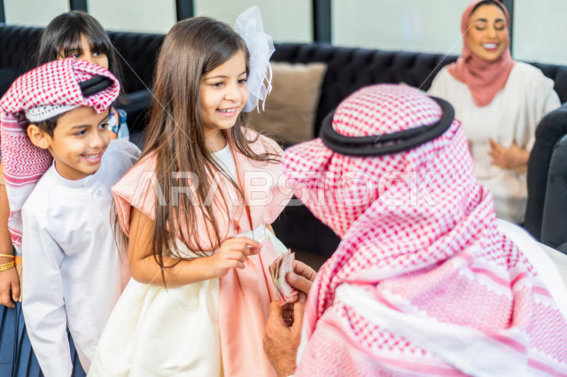تقديم العيدية للأطفال في عيد الفطر المبارك ، أجواء رائعة لعائلة سعودية داخل المنزل تحتفل بعيد الفطر السعيد ، عيد فطر مبارك ،  الزيارات العائلية وتجمعات الأسر ،  تقديم العيديات و الحلوى ، القرقيعان