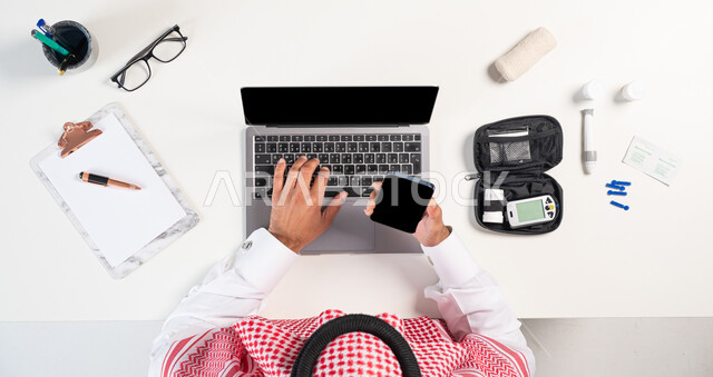 طلب مستلزمات وأدوات الطبية من خلال المواقع الالكترونية، بورتريه مقرب ليدي رجل عربي خليجي سعودي يستخدم الهاتف المحمول واللابتوب لطلب استشارة صحية عبر الانترنت وبجانبه جهاز قياس سكر الدم، بيع وشراء إبر الوخز لتحليل الدم أونلاين، عرض شاشة سوداء فارغة، خلفية بيضاء