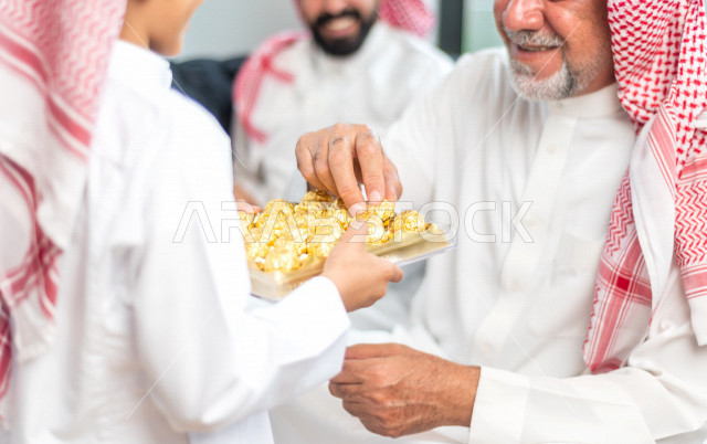 Sharing a wonderful atmosphere for a Saudi family inside the house celebrating Eid Al Fitr, Eid Al Fitr Mubarak, family visits and family gatherings, offering Eids and sweets, Gergean