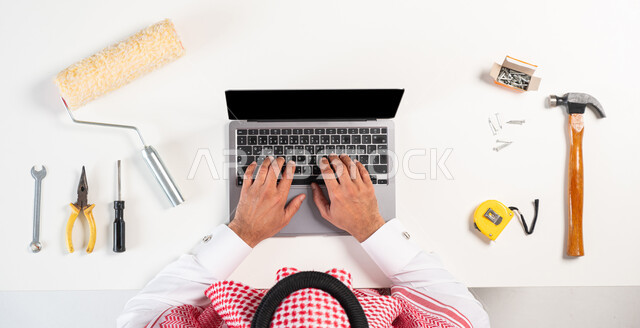 Purchasing maintenance and painting tools, the concept of electronic shopping, interest in renewal and development, a vertical portrait of a Saudi Gulf Arab man wearing a traditional thobe, using a computer, displaying a blank black screen, a white background
