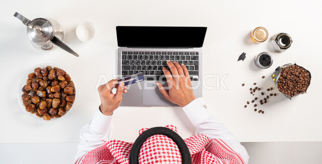 التسوق الإلكتروني عبر الحاسوب، الحصول على المأكولات والمشروبات أونلاين،  بورتريه لرجل عربي سعودي خليجي يرتدي ثوب سعودي تقليدي يقوم باستخدام الهاتف المحمول، استخدام أجهزة تقنية حديثة ، البيع والشراء عبر المواقع الإلكترونية، عرض شاشة سوداء فارغة، خلفية بيضاء