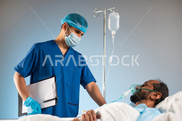 النظرات التي يملؤها التفاؤل والأمل والابتسامة، تقديم الاستشارات الطبية في المشافي، الرعاية الصحية والعلاج، بورتريه مقرب لرجل عربي خليجي سعودي مستلقي على السرير يرتدي يونيفورم العمليات يضع كمامة الأكسجين, اتباع الإجراءات الاحترازية من فايروس كورونا، خلفية زرقاء