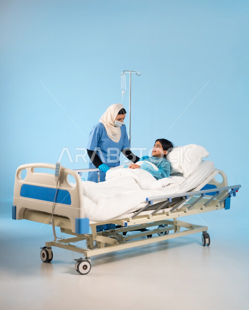 اتباع اجراءات الوقاية من فايروس كورونا, أهمية القيام بالفحوصات الدورية للأولاد, تقديم الدعم النفسي للمرضى, بورتريه لممرضة عربية خليجية سعودية ترتدي يونيفورم العمل والكمامة تقف بجانب الفتاة المريضة, مفهوم الطب والرعاية الصحية, خلفية زرقاء