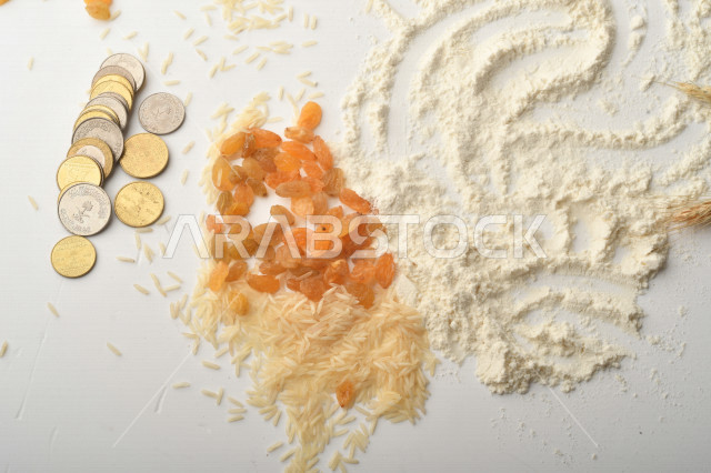 مجموعة من الأرز والزبيب والقمح والطحين والعملات المعدنية على خلفية بيضاء