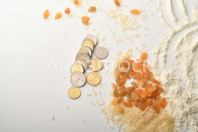مجموعة من الأرز والزبيب والقمح والطحين والعملات المعدنية على خلفية بيضاء