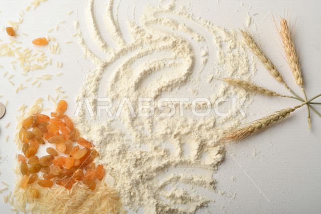 مجموعة من الأرز والزبيب والقمح والطحين والعملات المعدنية على خلفية بيضاء