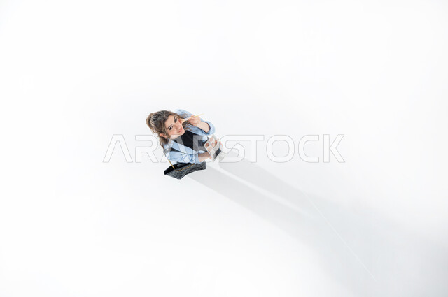 Applying foundation to hide skin imperfections, taking care of beauty and appearance, educational courses for makeup tutorial, Saudi cosmetics expert, vertical upper portrait of a Saudi Arabian Gulf woman wearing casual summer clothes holding a beauty blender and a mirror, white background