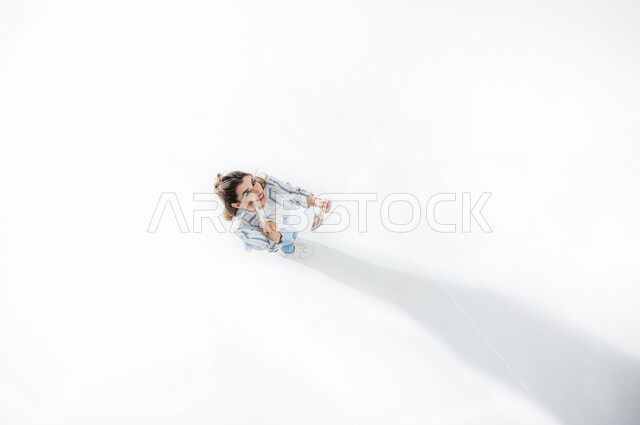 مفهوم الانوثه والإهتمام بالجمال والمظهر الخارجي، بورتريه عامودي علوي لشابه عربيه خليجيه سعوديه ترتدي الزي الكاجوال الصيفي تقوم بوضع مساحيق التجميل وأحمر الشفاه، خبيرة سعودية لمستحضرات التجميل النسائية، التسويق لمنتجات التجميل، مكياج وميكاب تتوريال, خلفيه بيضاء