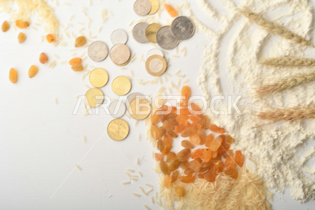 مجموعة من الأرز والزبيب والقمح والطحين والعملات المعدنية على خلفية بيضاء