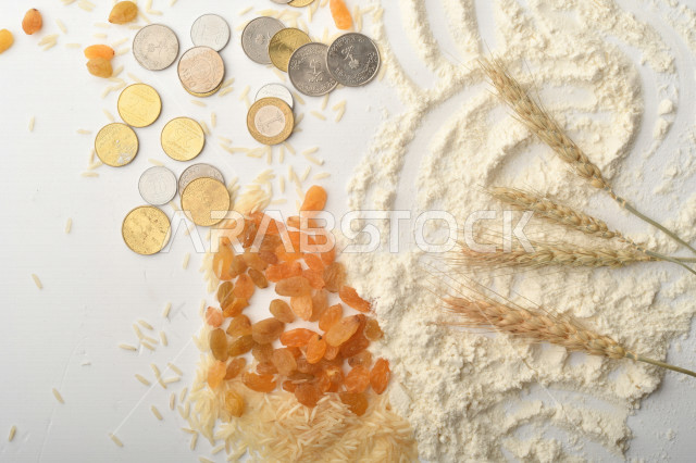مجموعة من الأرز والزبيب والقمح والطحين والعملات المعدنية على خلفية بيضاء
