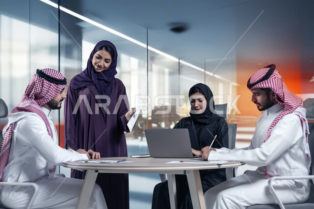 تطوير الاعمال والشركات باستخدام الاجهزة التقنية, اجتماع عمل وانجاز المشاريع, التركيز والعمل المتقن, الحوارات والنقاشات ضمن الفريق, مناقشة الخطط وشرح مهام الاعمال, زملاء عمل عرب سعوديين خليجيين في اجتماع, ارتداء اللباس السعودي التقليدي, خلفية المكتب