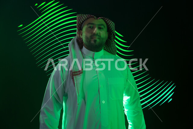 اضاءة خضراء على شكل خريطة المملكة العربية السعودية، الاحتفال بذكرى اليوم الوطني 23 سبتمبر، رجل عربي خليجي سعودي يرتدي الشماغ والثوب التقليدي يقف باستقامة بتعابير وايماءات الفخر والاعتزاز بالوطن، الحب والانتماء للبلاد