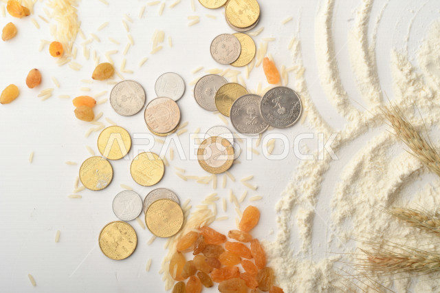 مجموعة من الأرز والزبيب والقمح والطحين والعملات المعدنية على خلفية بيضاء