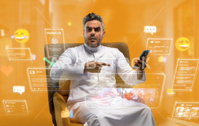 الاشارة إلى الهاتف المحمول بتعابير الغضب والانزعاج، تصفح وسائل التواصل الاجتماعي، استخدام التقنيات الحديثة، رجل عربي خليجي سعودي يرتدي الثوب التقليدي يجلس على كرسي يحمل جوال بتعابير عدم الرضا، خلفيه صفراء مع ايقونات وفقاعات المحادثات والايموجيز
