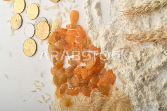 مجموعة من الأرز والزبيب والقمح والطحين والعملات المعدنية على خلفية بيضاء