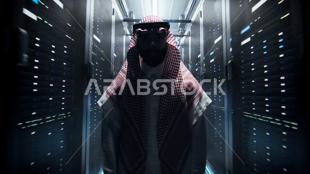 شبكة تخزين البيانات، صورة ظلية لرجل عربي خليجي سعودي يرتدي الشماغ والثوب التقليدي يقف في مركز الداتا سنتر، حظيرة الخوادم والبيانات وتخزينها، التطور الرقمي وتكنولوجيا المستقبل، مفهوم التحول الرقمي، غرفة التحكم بالسيرفرات وخوادم الانترنت