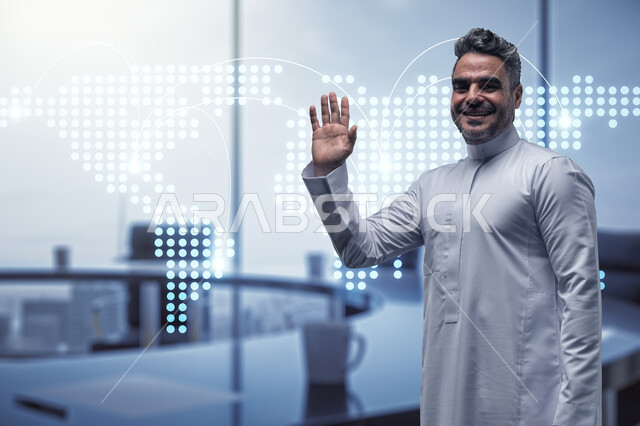 التلويح باليد والسلام عن بعد، صورة مقربة لرجل عربي سعودي خليجي مبتسم يرتدي الثوب التقليدي يرفع يده للأعلى, مفهوم الاستقبال والترحيب, ايماءات وتعابير السرور, بيئة العمل المريحة في الشركات السعودية, خلفية المكتب مع ايقونات هولوجرامية