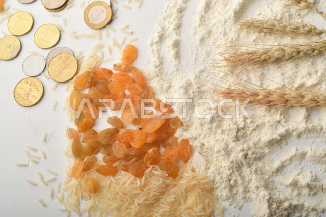 مجموعة من الأرز والزبيب والقمح والطحين والعملات المعدنية على خلفية بيضاء