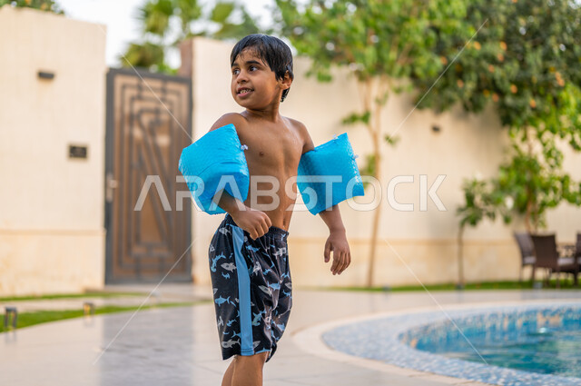 استخدام عوامة السباحة للقفز في المسبح، رحلة سياحية ترفيهية، قضاءعطلة صيفية سعيدة، ولد عربي خليجي سعودي يستعد ليقفز في بركة مائية، الاستمتاع بالأجواء الصيفية الممتعة