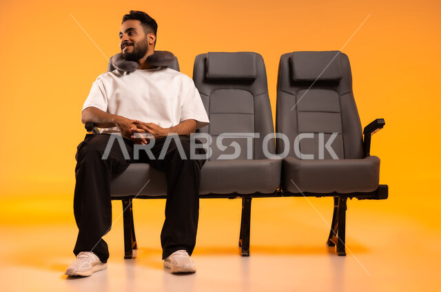 الشعور بالراحة والطمأنينة، مفهوم الاسترخاء والاستمتاع بالأجواء الهادئة، الاستعداد للسفر في إجازة صيفية، الجلوس في صالة المطار, بورتريه لرجل عربي خليجي سعودي يرتدي الزي الكاجوال يجلس على المقعد يضع وسادة النوم , أهمية السياحة في السعودية، خلفية برتقالية