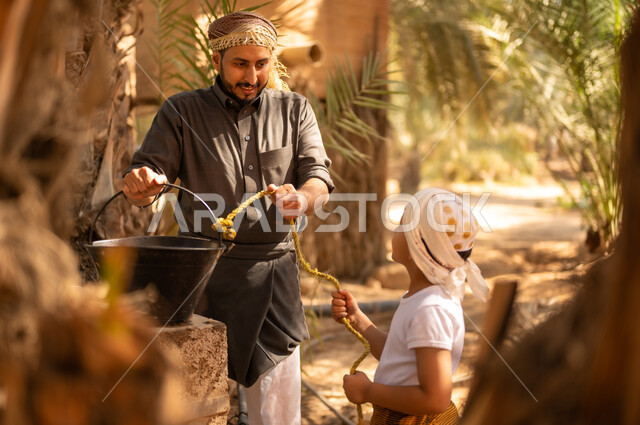مشاركة الأولاد في العمل داخل مزارع النخيل المثمرة في المملكة، استعمال الطرق القديمة والشعبية في الحصول على الماء، فلاح عربي خليجي سعودي يرتدي الثوب والعمامة يقوم بمساعدة ولده للحصول على المياه من البئر في المزرعة، توريث المهن الزراعية التقليدية المحلية