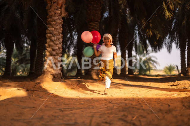 Gestures of joy and joy, spending time and playing outdoors, a smiling Saudi Gulf Arab child wearing a harvest uniform and turban running and carrying a group of colorful balloons inside fruitful palm farms, preserving a rich agricultural heritage, traditional Saudi occupations
