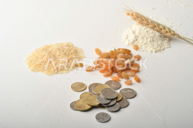 مجموعة من الأرز والزبيب والقمح والطحين والعملات المعدنية على خلفية بيضاء