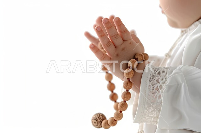 مفهوم الإجتهاد في العباده و التقرب الى الله في شهر رمضان المبارك, الإكثار من ذكر الله تعالى والإستغفار والدعاء, تصوير مقرب لأيدي ولد عربي سعودي خليجي يرتدي الثوب الأبيض يرفع يديه يمسك السبحه, يوم الجمعه المباركه، خلفيه بيضاء