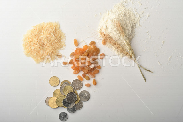 مجموعة من الأرز والزبيب والقمح والطحين والعملات المعدنية على خلفية بيضاء