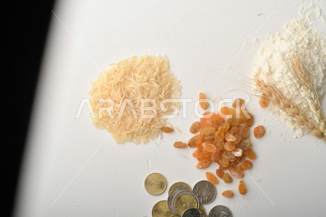 مجموعة من الأرز والزبيب والقمح والطحين والعملات المعدنية على خلفية بيضاء