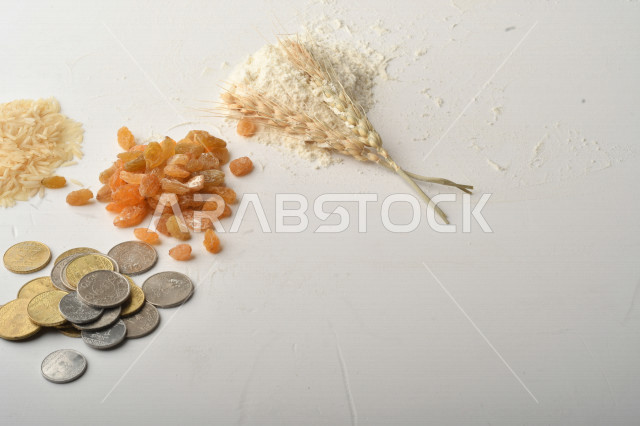 مجموعة من الأرز والزبيب والقمح والطحين والعملات المعدنية على خلفية بيضاء