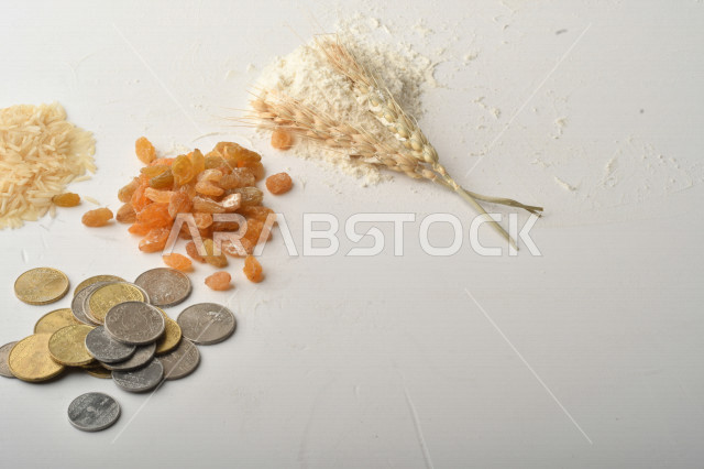 مجموعة من الأرز والزبيب والقمح والطحين والعملات المعدنية على خلفية بيضاء