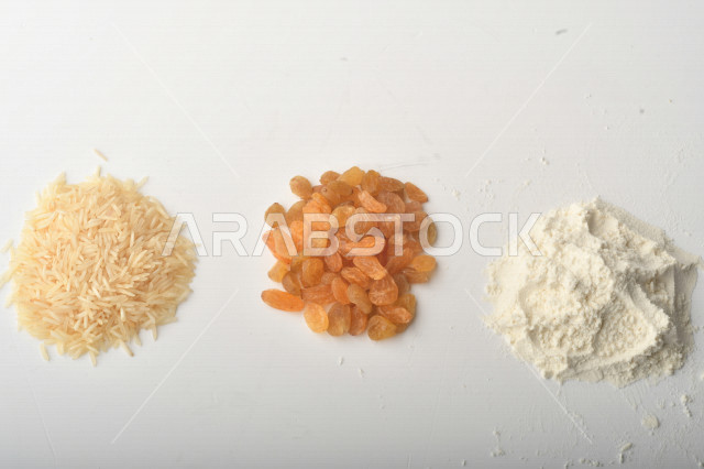 Handful of rice, wheat, raisins and flour on white background