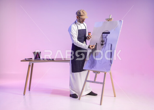 القيام برسم لوحة معالم وعلم المملكة، إحياء ذكرى اليوم الوطني السعودي، استخدام ريشة الرسم والتلوين، التباهي والفخر بالهوية السعودية، بورتريه لرسام عربي خليجي سعودي يرتدي الثوب التقليدي ومريلة الرسم، النظر للوحة بتعابير الفرح، الجسم بالطول الكامل، خلفية ملونة