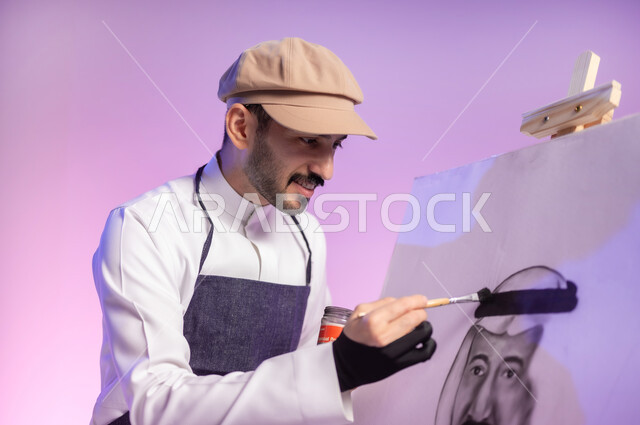 استخدام ريشة الرسم والتلوين، القيام برسم لوحة معالم وعلم المملكة، النظر للوحة بإيماءات السعادة، التباهي والفخر بالهوية السعودية، حب الوطن والإنتماء إليه، إحياء ذكرى اليوم الوطني، بورتريه مقرب لرسام عربي خليجي سعودي يرتدي الثوب التقليدي ومريلة الرسم، خلفية ملونة