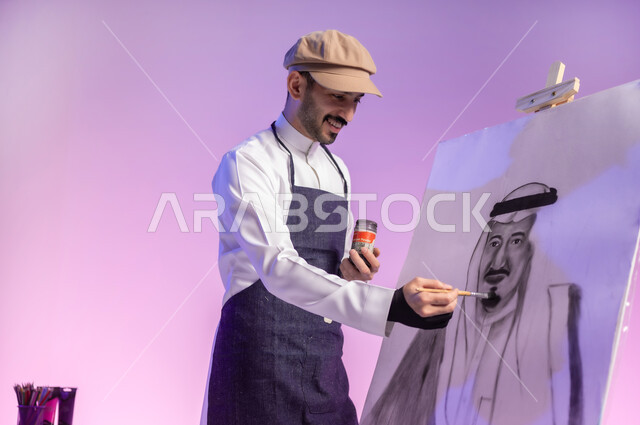 القيام برسم لوحة معالم وعلم المملكة، النظر للوحة بإيماءات السعادة، التباهي والفخر بالهوية السعودية، حب الوطن والإنتماء إليه، إحياء ذكرى اليوم الوطني، بورتريه مقرب لرسام عربي خليجي سعودي يرتدي الثوب التقليدي ومريلة الرسم، استخدام ريشة الرسم والتلوين، خلفية ملونة