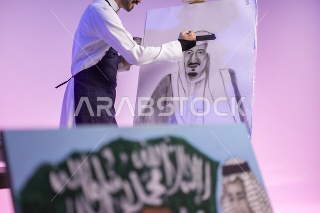 القيام برسم لوحة وطنية، الوقوف أمام لوحة معالم وعلم المملكة، بورتريه مقرب لرسام عربي خليجي سعودي يرتدي الثوب التقليدي ومريلة الرسم، استخدام ريشة الرسم والتلوين، إحياء ذكرى اليوم الوطني، ممارسة هواية الفنون اليدوية، خلفية ملونة