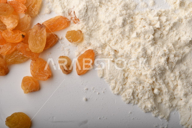 حفنة من الأرز والزبيب والطحين مصورة على خلفية بيضاء .