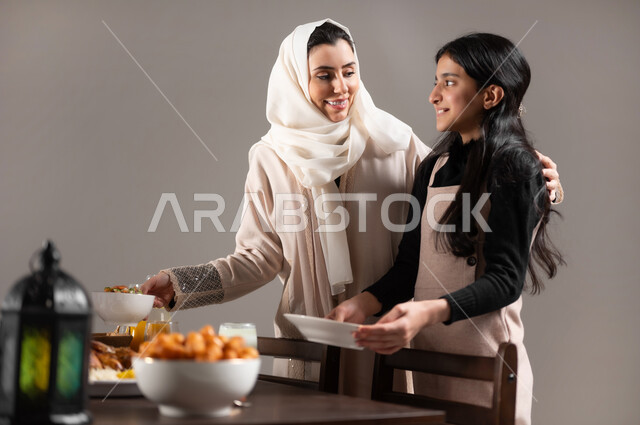 الترابط العائلي و شعور الابناء بالحب و الامان, بورتريه مقرب لأم عربيه خليجيه سعوديه تقوم بتحضير افطار رمضان مع ابنتها, المناسبات و الاعياد الاسلامية, ايماءات السعادة بمناسبة قدوم الشهر الفضيل, خلفية رمادية