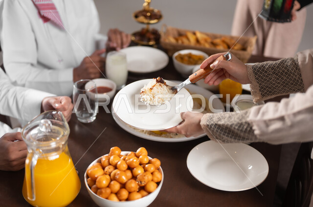 احترام المرأة لزوجها, بورتريه مقرب لزوجة عربية خليجية سعودية تقدم كأس من اللبن للزوج على مائدة الافطار, ايماءات السعادة و السرور بقدوم شهر رمضان, الاحتفال بالاعياد و المناسبات الاسلامية, المأكولات الشهية على السفرة, الاستمتاع بالمشروبات الباردة اللذيذة, خلفية رمادية