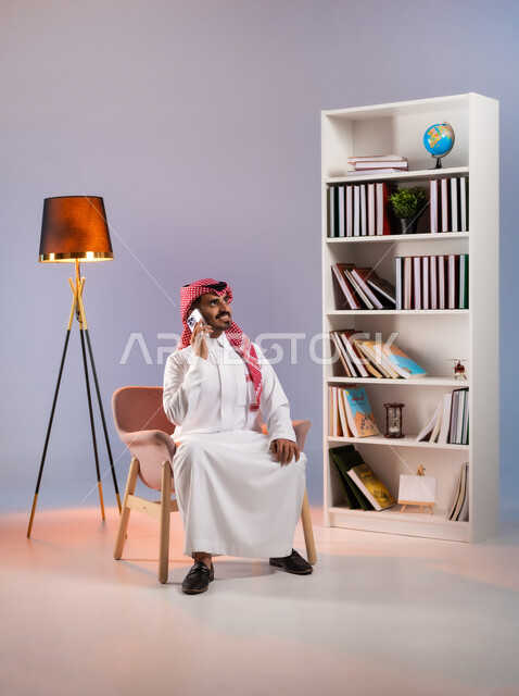 الاستمتاع بتبادل الأحاديث والأخبار, إجراء مكالمة هاتفية عبر الجوال, بورتريه لرجل عربي خليجي سعودي يرتدي الثوب التقليدي والشماغ يستخدم الهاتف المحمول, التواصل مع الأقارب والأصدقاء عبر وسائل التواصل الاجتماعي, خلفية ملونة