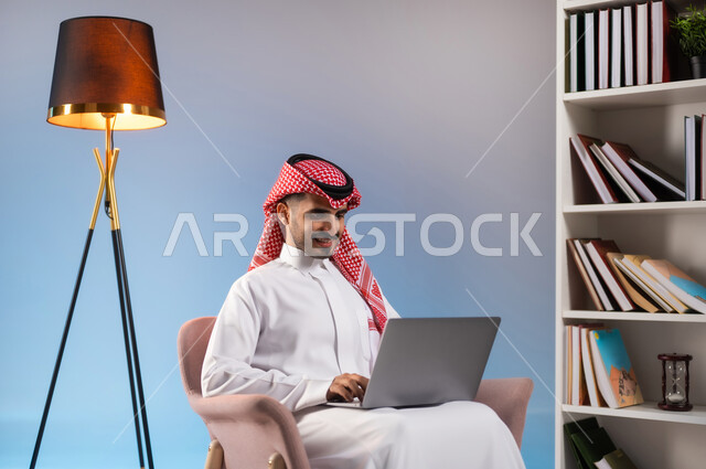 انجاز المهام عبر الانترنت, التسوق الالكتروني والشراء عبر التطبيقات والتقنيات الحديثة, بورتريه لرجل عربي خليجي سعودي يرتدي الثوب التقليدي والشماغ يعمل على الحاسب المحمول, استخدام الأجهزة المتطورة في المملكة, إدراة الأعمال عن بعد, خلفية ملونة