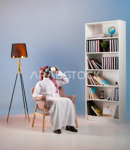 مشاهدة أفلام الواقع الافتراضي بإيماءات الاندماج والتفاعل, الترفيه والتسلية في وقت الفراغ, بورتريه لرجل عربي خليجي سعودي يرتدي الثوب التقليدي ونظارة في آر ثلاثية الأبعاد يقوم بقضاء وقت ممتع, محاكاة العالم الخيالي, خلفية ملونة
