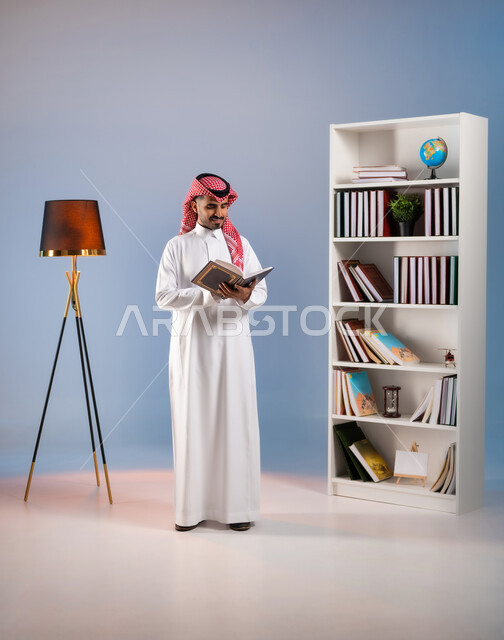 Developing cultural repertoire, the concept of culture and self-learning, reading interesting stories and novels, a portrait of a Saudi Gulf Arab man wearing the traditional dress and shemagh, holding a book in his hand, spending leisure time practicing the hobby of reading,, full-length body portrait, colored background