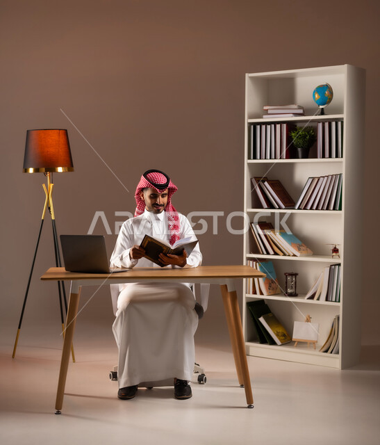 ممارسة هواية المطالعة, مفهوم الثقافة والتعلم الذاتي, الاستمتاع بالأنشطة الترفيهية المفيدة في وقت الفراغ, قراءة القصص والروايات, بورتريه لرجل عربي خليجي سعودي يرتدي الثوب التقليدي والشماغ يحمل بيده كتاب, استخدام الأجهزة والتطبيقات الالكترونية الحديثة, خلفية بيج